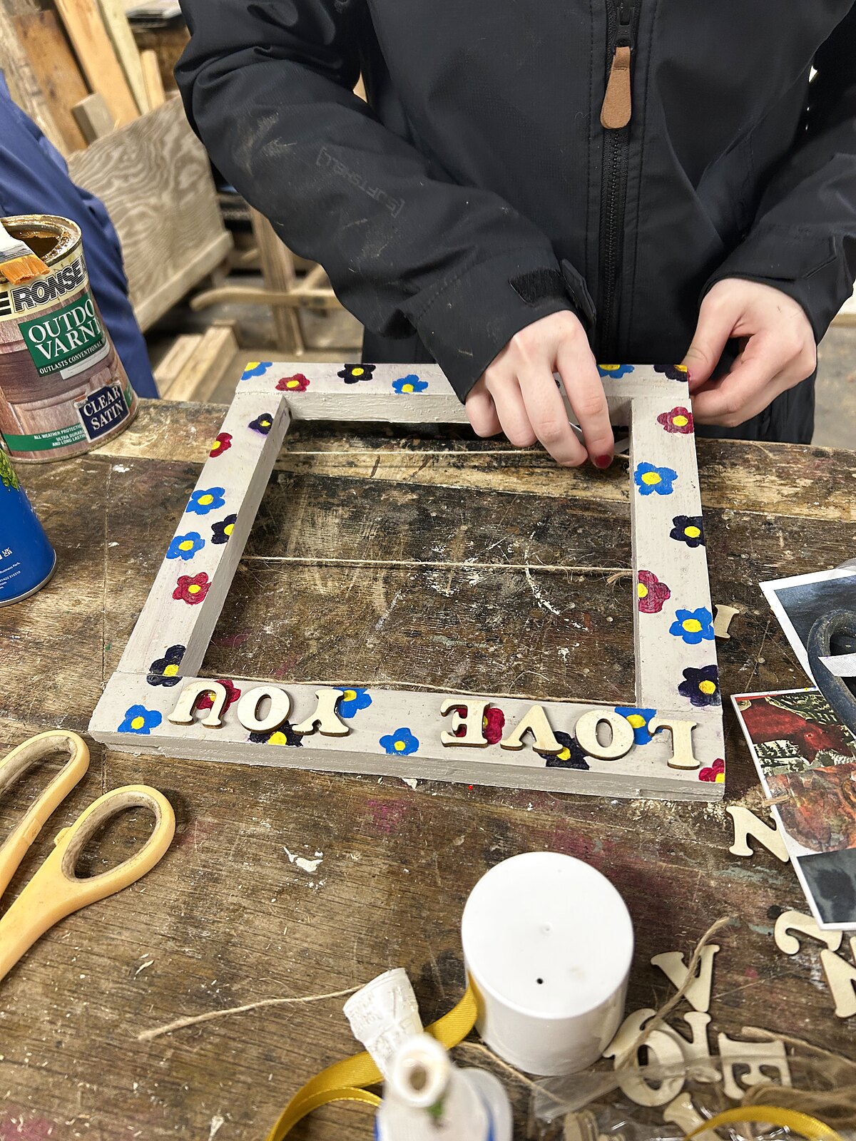 A decorated wooden photo frame being finished at the Wild Minds craft bench